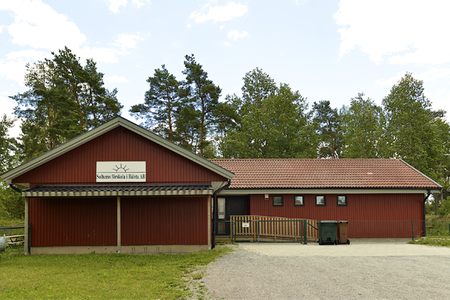 Solhems förskola – rött trähus med skylt bland tallar
