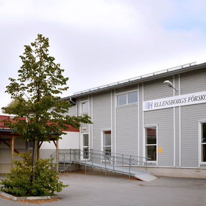 Ellensborgs förskola i Bålsta med ljusgrå träfasad, vit skylt, ramp och glasentré