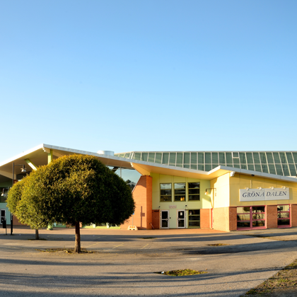 Gröna Dalenskolan i Bålsta med vinklad takform, gul puts, glasentré och tegelsektioner