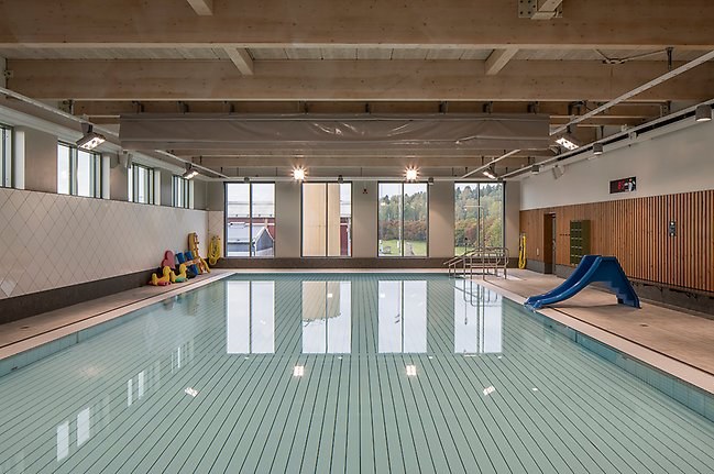 Multibassängen i Bålsta simhall med lugnt vatten och en barnrutchkana vid kanten