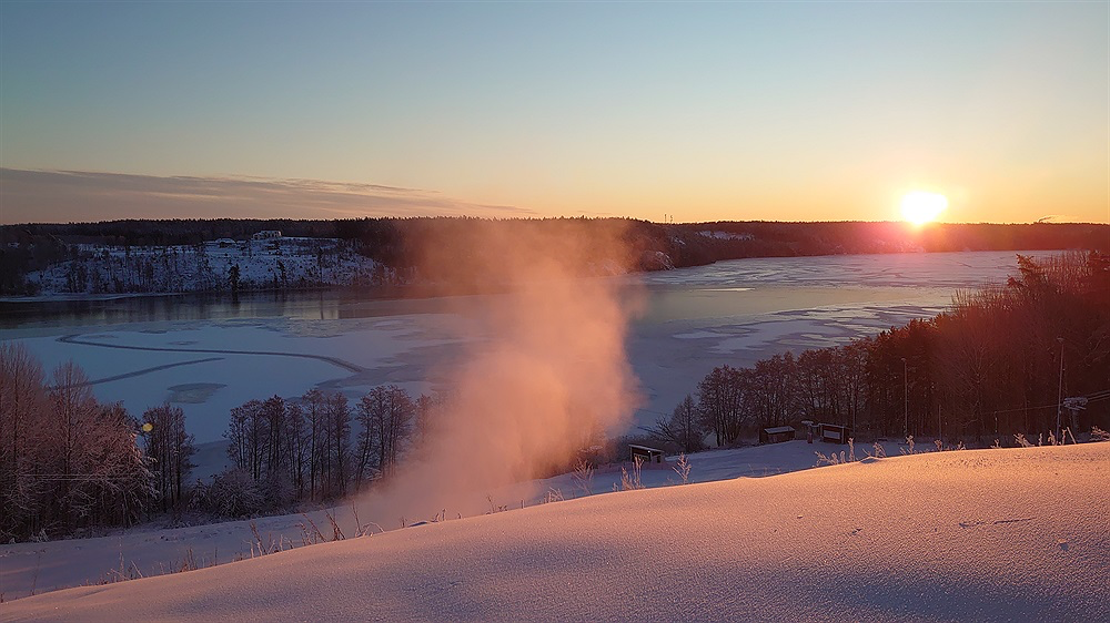 Solen går ner över den snötäckta backen och Mälaren i Granåsen, Bålsta