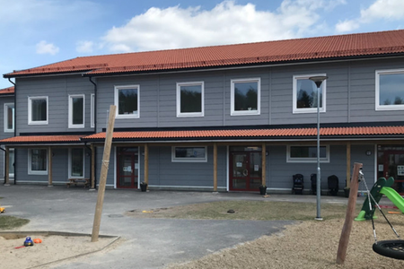 Väppeby förskola – grå fasad, rött tak och lekplan